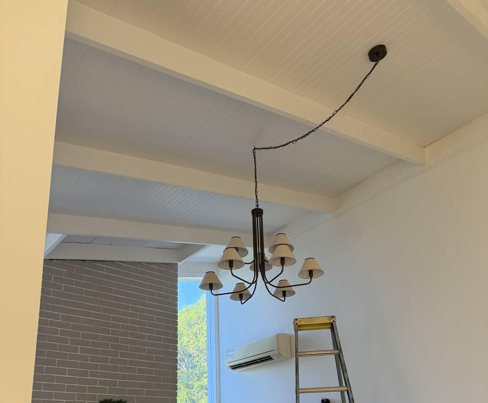 Chandelier hung from a raked timber-lined ceiling