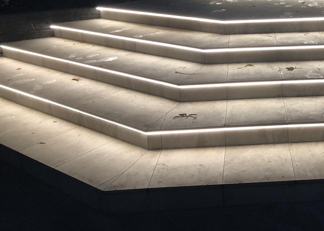 Recessed LED strip lighting along the nosing of wide garden steps at night