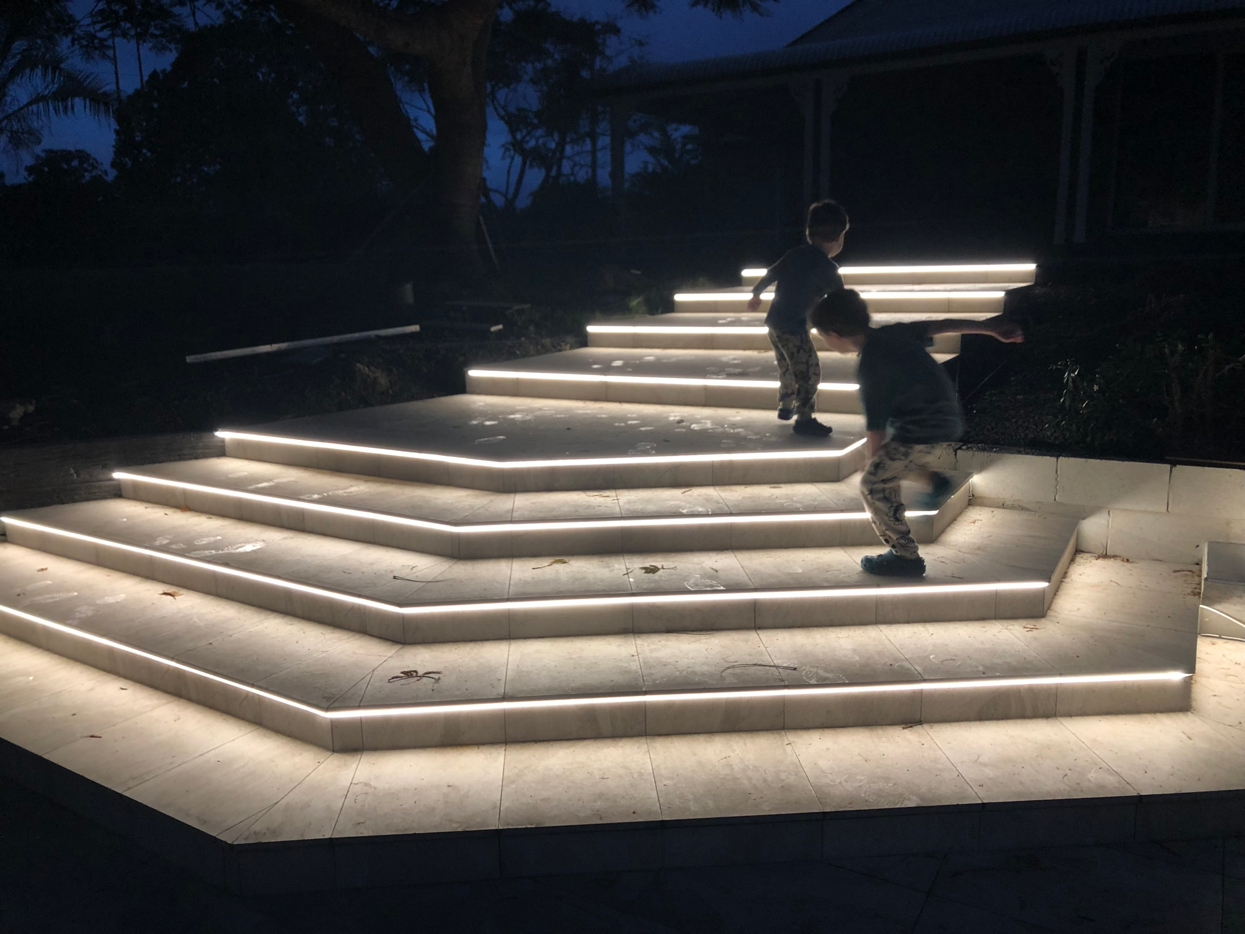 Garden staircase fitted with recessed LED strip lighting along each step at dusk
